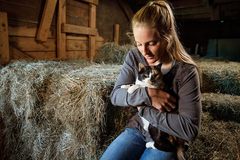 Woman holding cat in barn