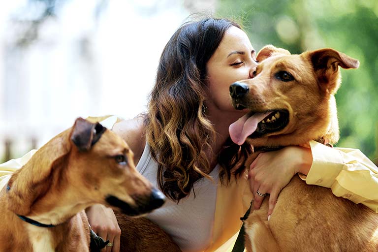 woman hugging two dogs