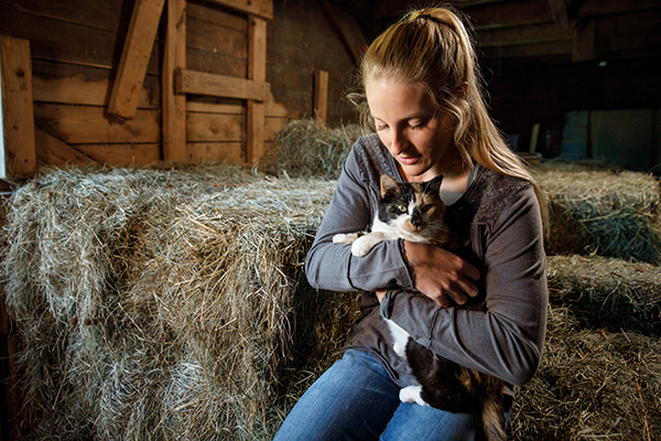 woman holding a kitten in barn