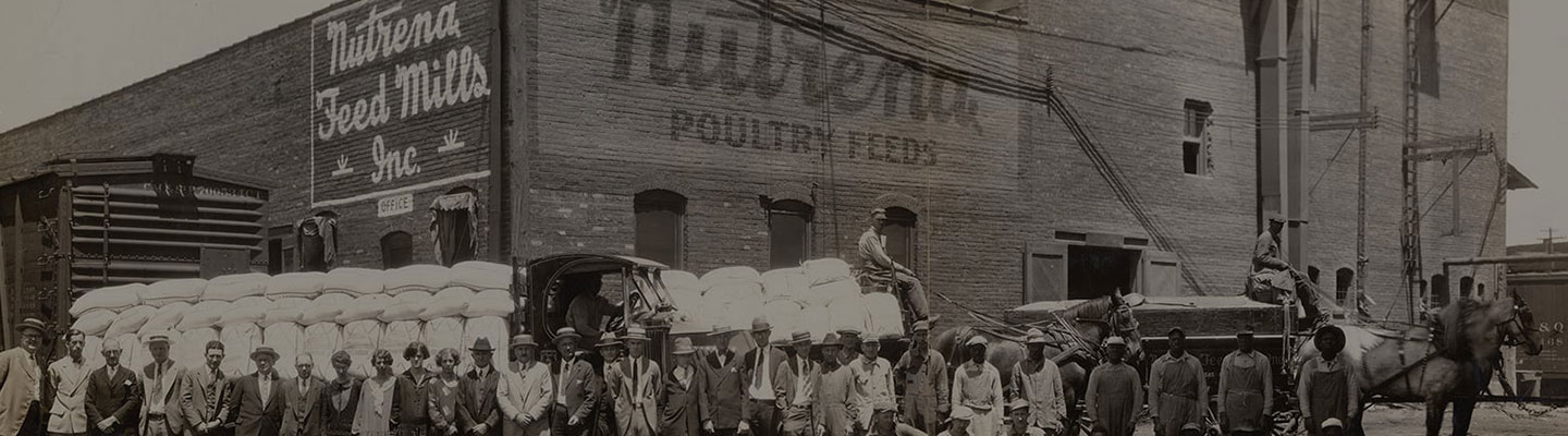 Historical photo of Nutrena employees standing outside of feed mill