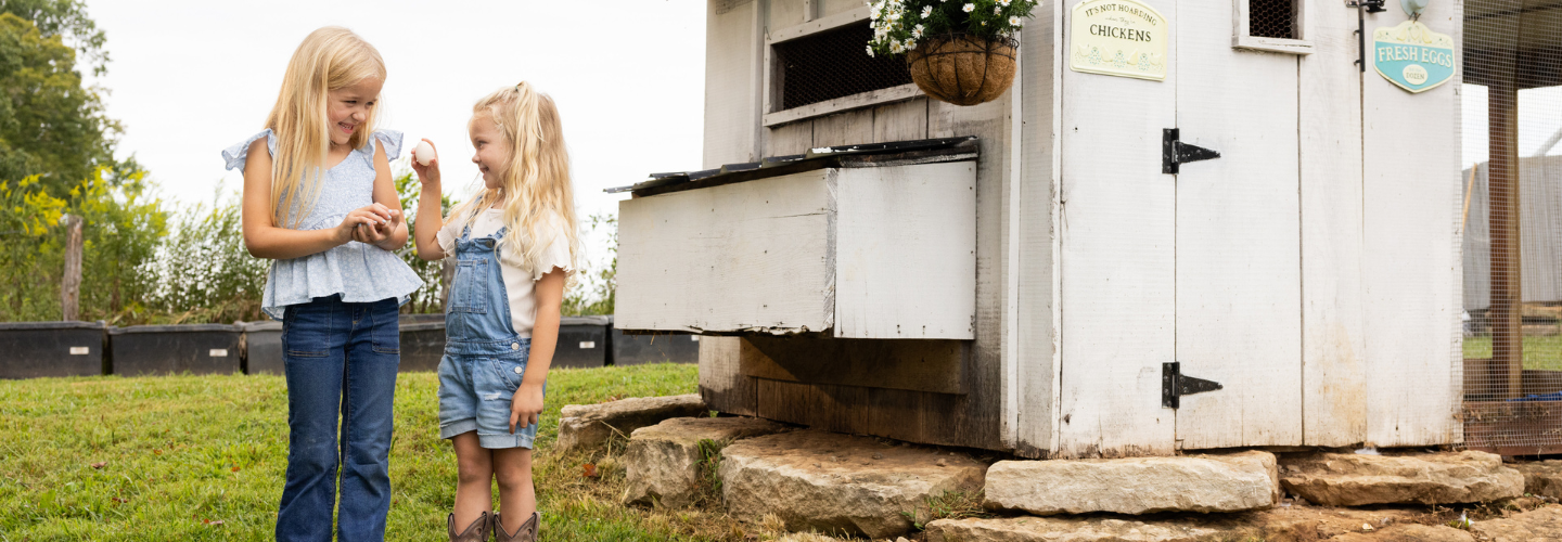 girls with chickens by chicken coop