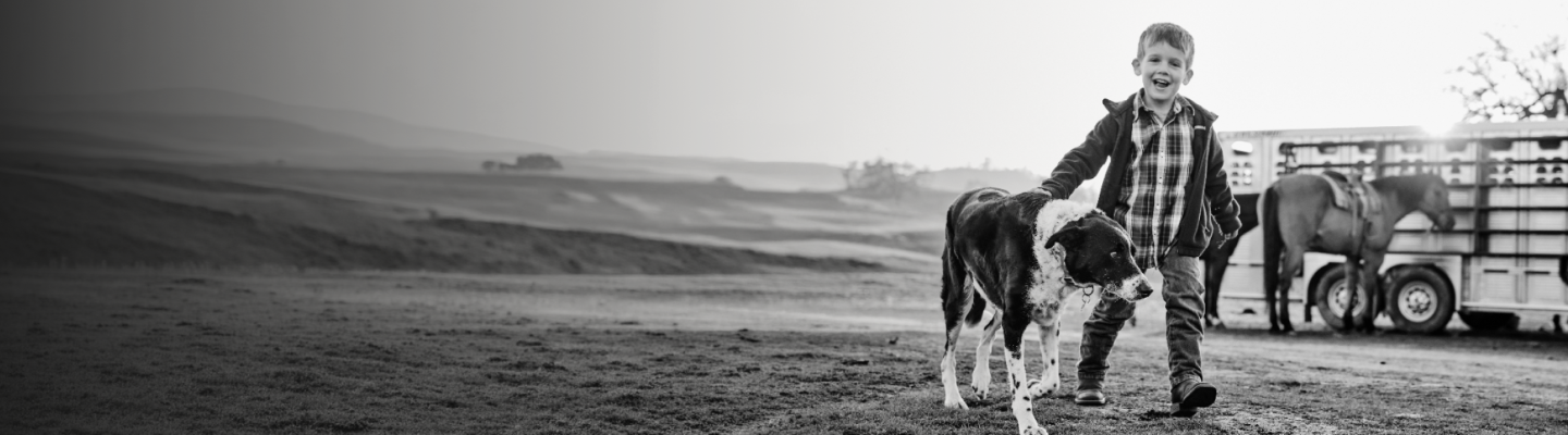 boy walking on farm with dog
