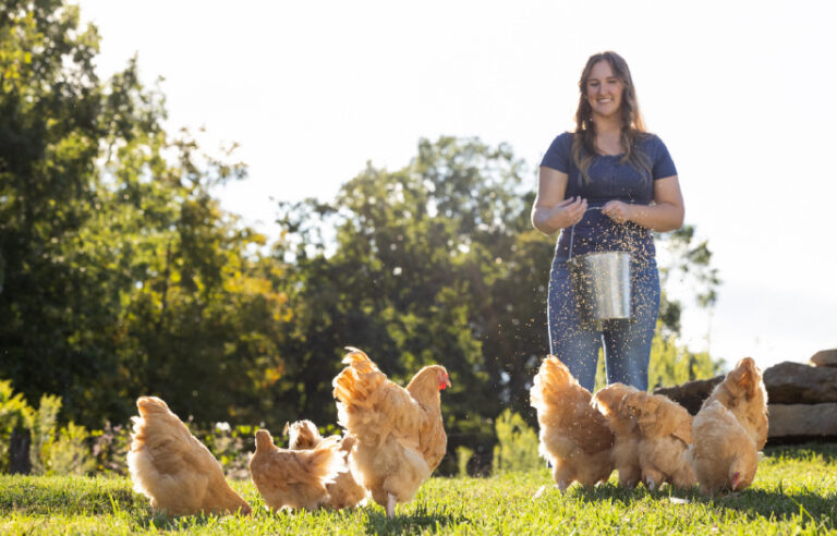 Women feeding her flock Nutrena NatureWise poultry feed to support their gut health